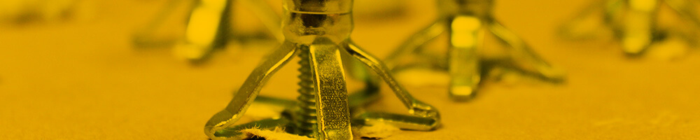 Nahaufnahme eines Hohlraumdübels, der hinter einer Wand installiert ist. Der Dübel ist in einer aufgeweiteten Position, um sicheren Halt in einem Hohlraum zu gewährleisten. Die Umgebung ist in einem gelblichen Farbton gehalten.