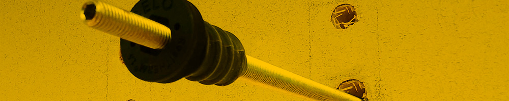 Nahaufnahme eines CELO ResiTHERM Abstandsmontagesystems, welches in eine gedämmte Wand montiert wird. Der Dübel ist in einem gebohrten Loch positioniert, das durch die Dämmstoffschicht führt.