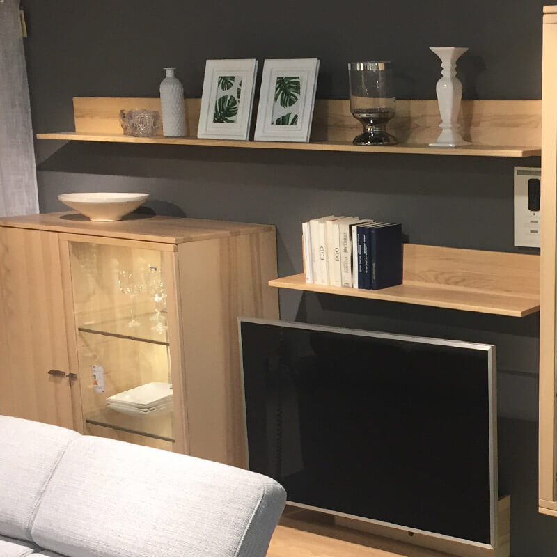 Ein Wohnzimmer mit modernen Holzregalen, die an einer dunklen Wand befestigt sind.