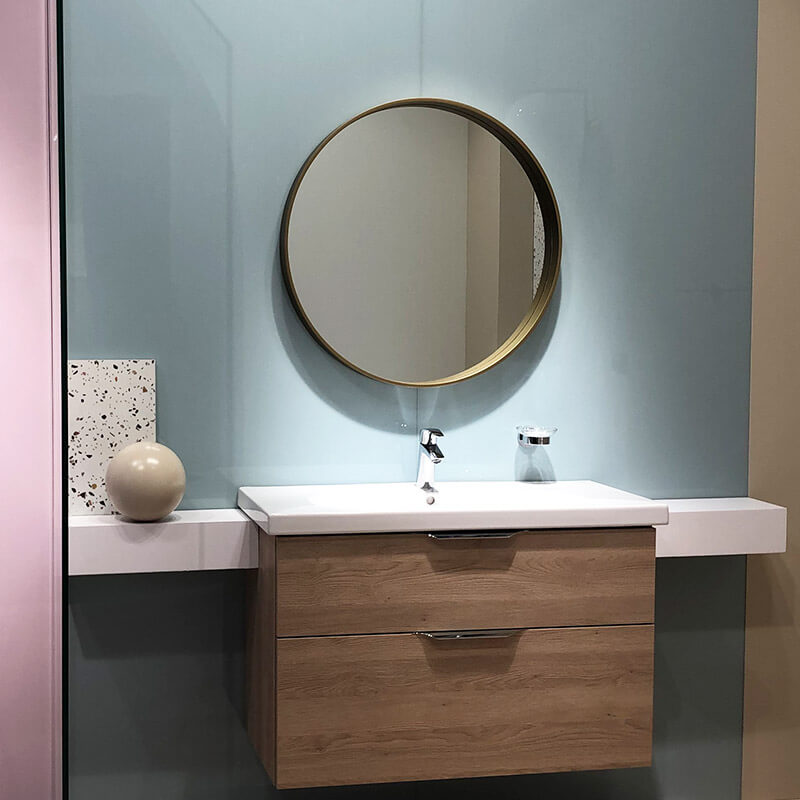 Ein modernes Badezimmer mit einem runden Spiegel über einem Waschbecken. Das Waschbecken ist auf einem hölzernen Waschtischunterschrank montiert.