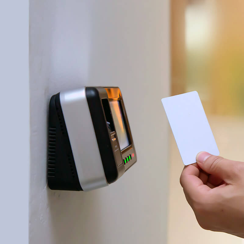 Eine Hand hält eine weiße Karte vor ein an der Wand befestigtes Kartenlesegerät. Das Lesegerät ist mit Dämmstoffdübeln an der Wand montiert, um eine sichere und dauerhafte Befestigung in gedämmten Wänden zu gewährleisten.