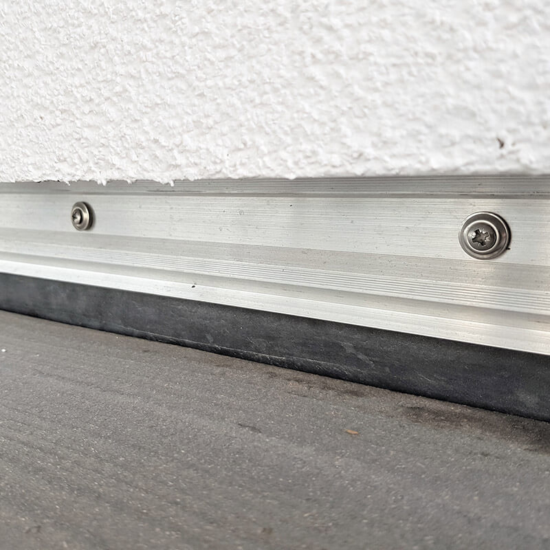 Eine Nahaufnahme einer Kappleiste, die an einer verputzten und gedämmten Hauswand befestigt ist. Die Schiene ist mit CELO-Dämmstoffdübeln sicher verankert, um eine stabile Befestigung an der gedämmten Fassade zu gewährleisten.