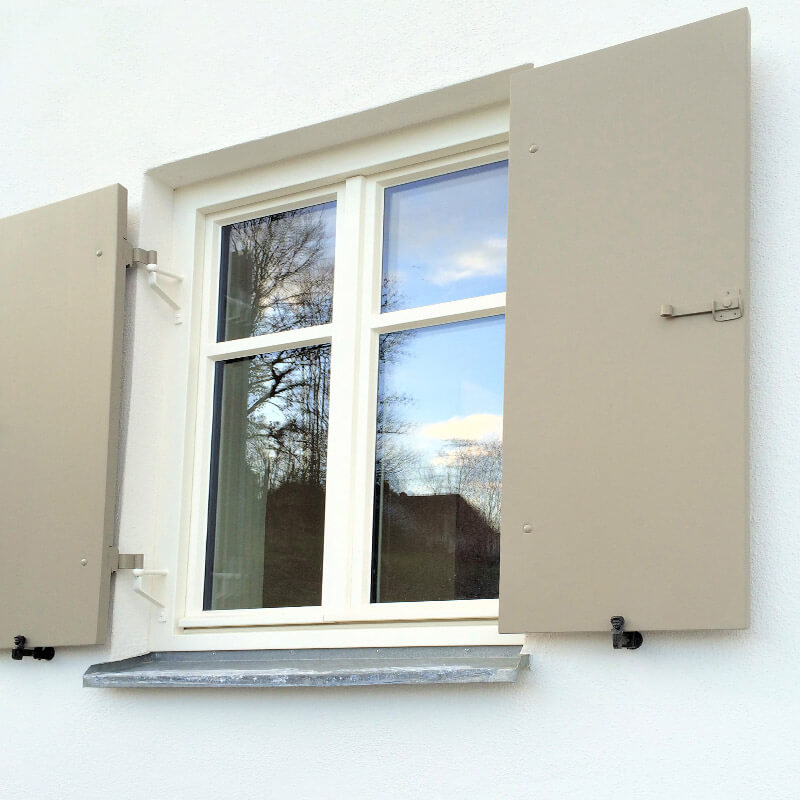 Ein Fenster mit geöffneten Fensterläden an einer gedämmten Fassade. Die Fensterläden sind mit CELO-Dämmstoffdübeln sicher montiert, um eine stabile Befestigung an der gedämmten Hauswand zu gewährleisten.