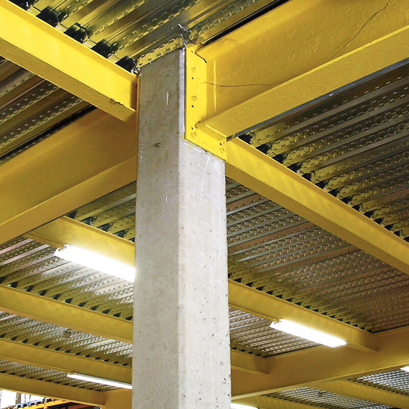 Stahlbalken in einer Industriehalle an eine Betonstrebe befestigt.