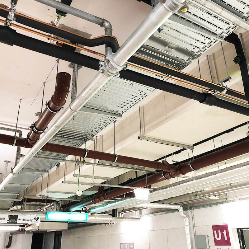 Verschiedene Rohrleitungen an einer Tiefgaragendecke befestigt.