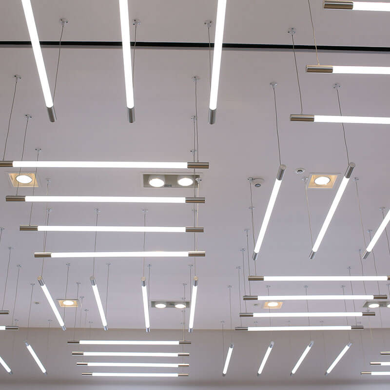 Mehrere moderne, rechteckige Deckenleuchten, die an einer weißen Decke befestigt sind.