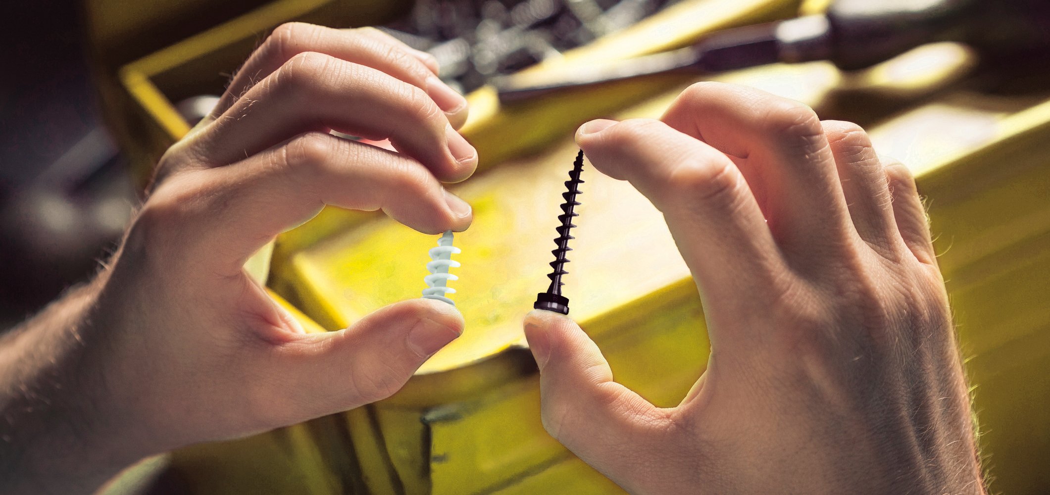 Zwei Hände halten jeweils eine weiße und eine schwarze Schraube