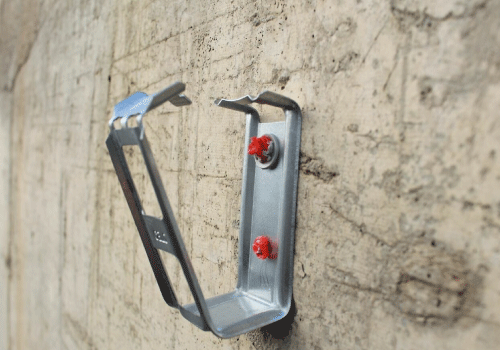 ETA-zugelassenes Gasnagler-Zubehör Kabelsammelhalter CHS, das Anwendungsbild zeigt die an einer Betonwand montierte Schelle geöffnet für die Aufnahme von Kabeln